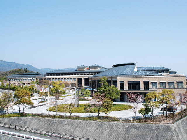 【管理棟・教育研究棟・体育館】瀬戸内海に向かう校舎棟の伸びやかな大屋根と講堂のおおらかな曲線の屋根が特徴的です。