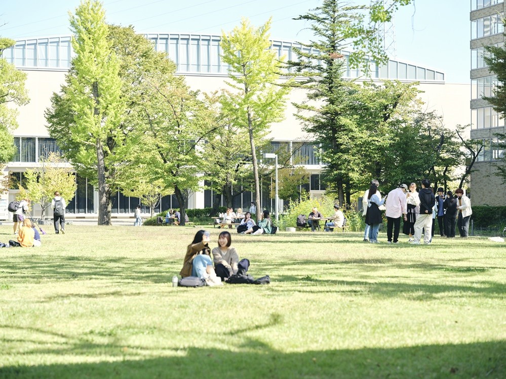 【芝生広場】晴れた日には、くつろぐ学生たちで賑わう憩いのスペース。小川にはホタルが生息する。